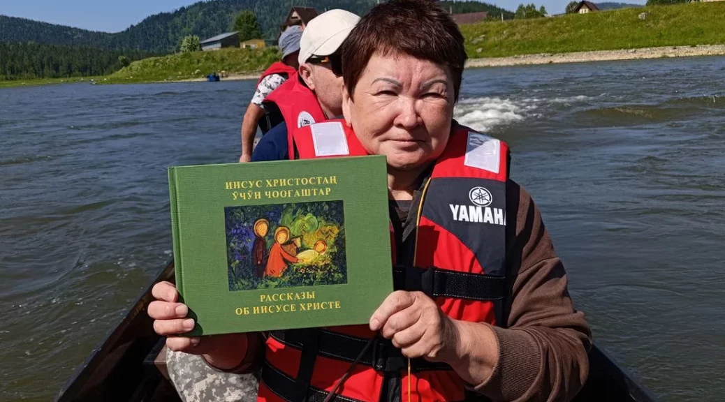 Lidé národa Shoria jedou po řece na lodi a vezou si knihy bible přeložené do svého jazyka